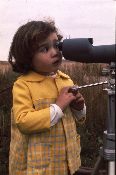 A small child looks through a telescope