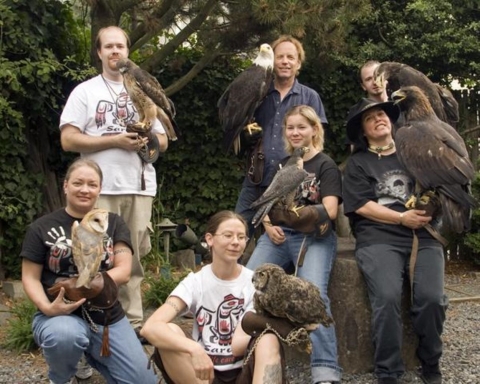 Photo of Leslie Zacher with the Sarvey Wildlife Care Center Education Team. Zacher is kneeling at the lower far left. There are six members of the team, each holding a bird.
