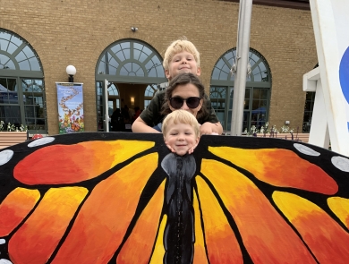 2 small children pose and adult behind a monarch butterfly cutout