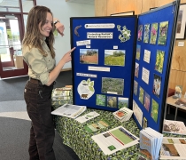 a woman in usfws uniform pointing to a display on invasive species