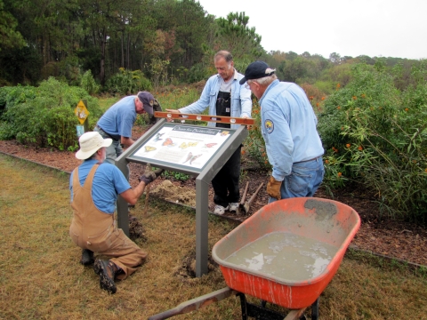 Volunteers at Pinckney Island National Wildlife Refuge installing a new interpretive wayside panel at the butterfly garden.