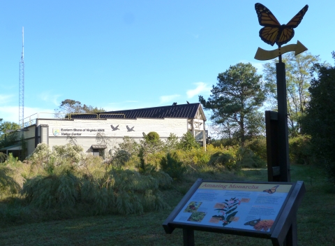A visitor center in the background with gardens and an interpretive sign in the foreground