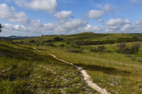 A trail winds across rolling hills and grasslands