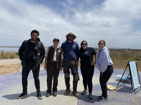 Five individuals from an environmental education program stand side by side and smile for a photo. 