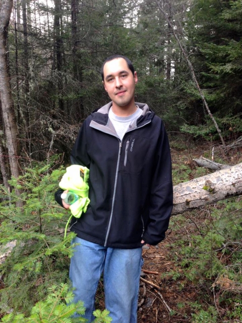  A man stands in a forest holding a neon article of clothing