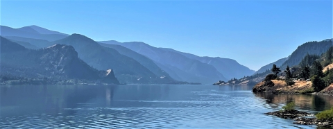 A view of calm water in the Columbia River with mountains in the background