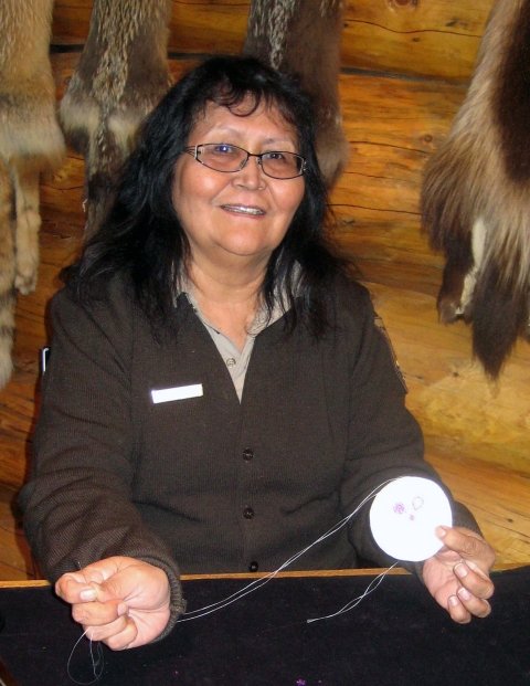 a woman in USFWS uniform shows her beading to the camera