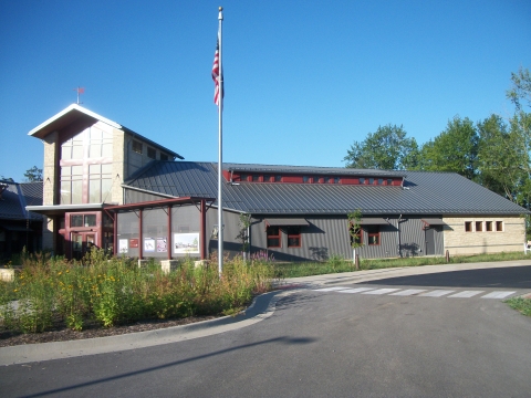 A modern building with a gray metal roof, and stone and metal siding. An American flag is in front.