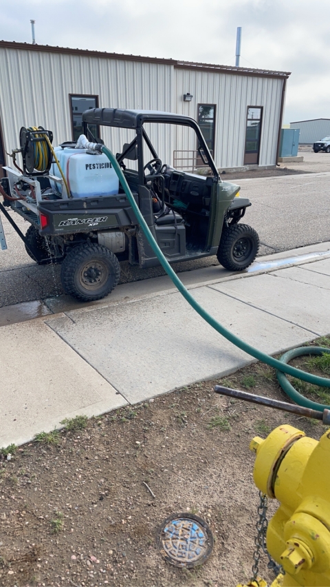 ATV with a container labeled pesticide and a hose attached to the container