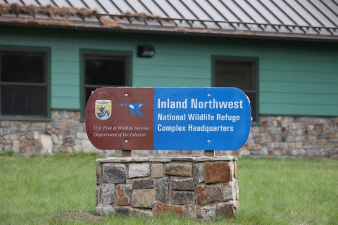 A brown and blue sign that reads "Inland Northwest National Wildlife Refuge Complex Headquarters"