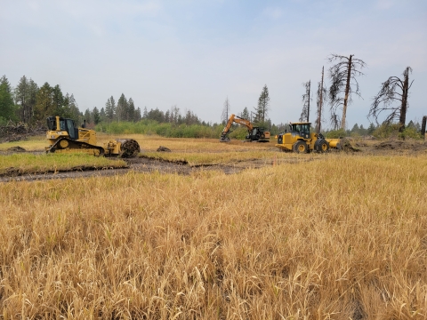 Large earth moving machines work to restore a wetland