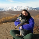 a woman and her dog with mountains in the background