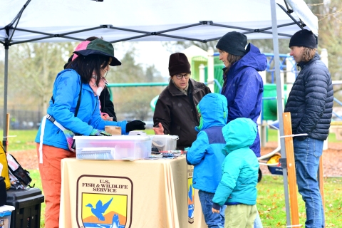 Two families pick-up bilingual activity kits and do a wetland game at one of the Winter Wildlife Field Days tents