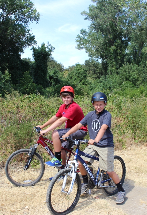 two kids on bicycles on dirt road