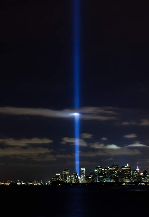 A bright beam of light reaching vertically into the sky from the New York City night skyline.