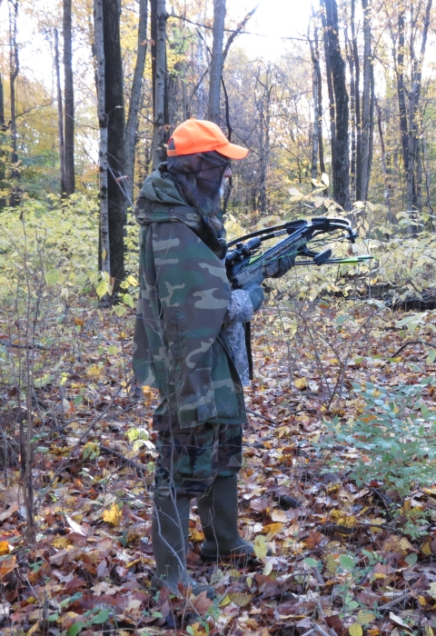 Archery hunter holding bow in woods