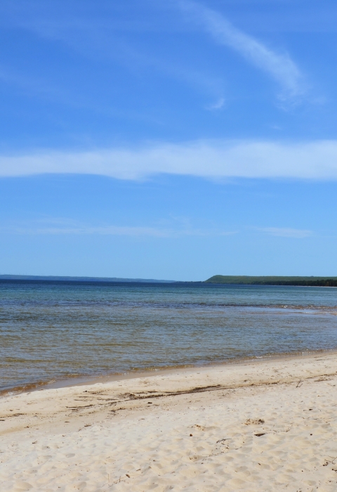 Calm water washes up on sandy beach.