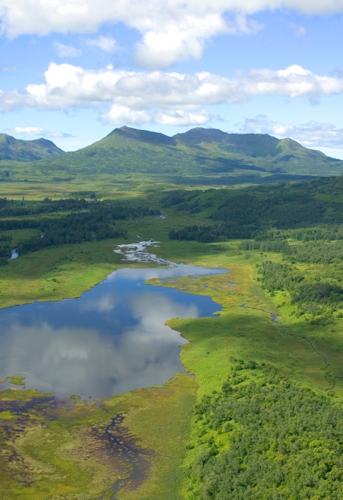 Clouds reflect in a wetland surrounded by mountains.