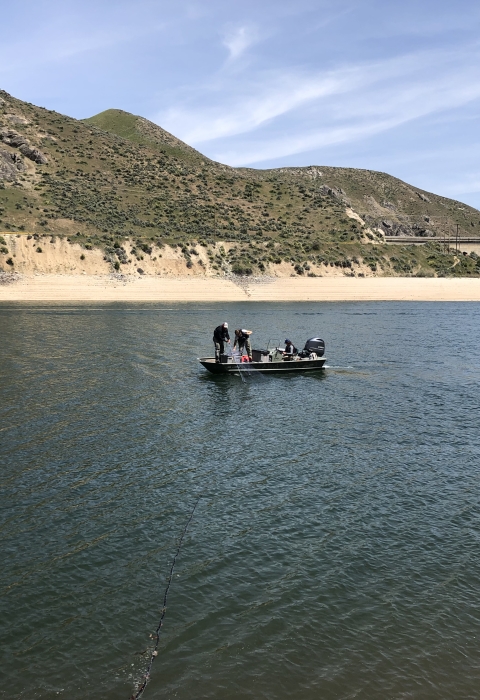 A boat can be seen on the reservoir with mountains in the background. 