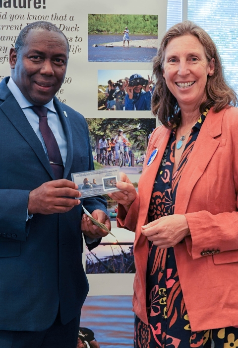 Assistant Director for Migratory Birds, Jerome Ford, stands with Director Martha Williams as they hold the newly issued duck stamp.