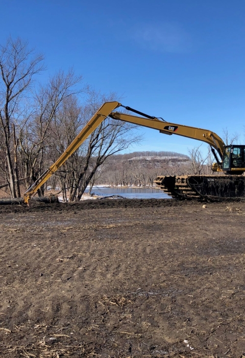 An excavator is moving dirt on an island of the river