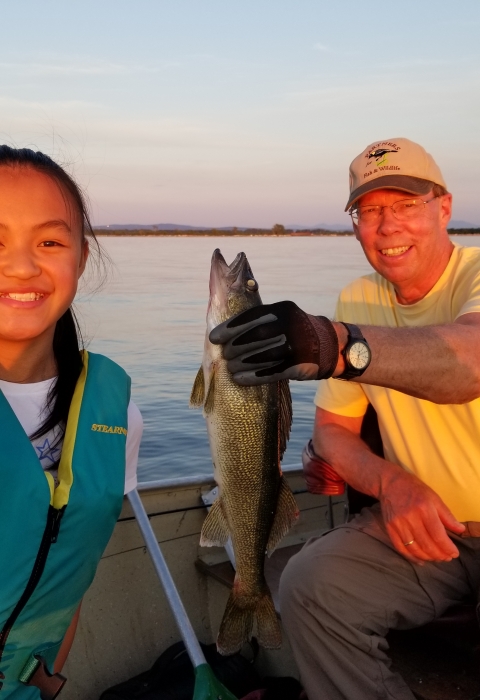 The author and his daughter in a fishing boat holding a fish
