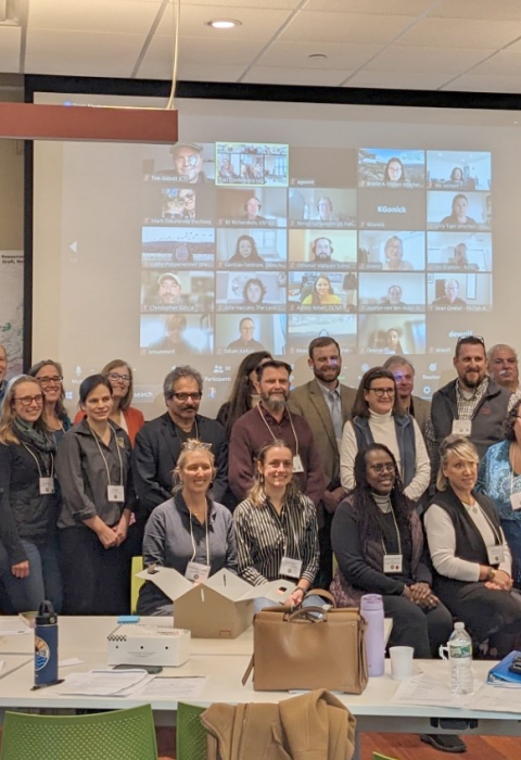 A large group of people in a conference room pose for a photo. 