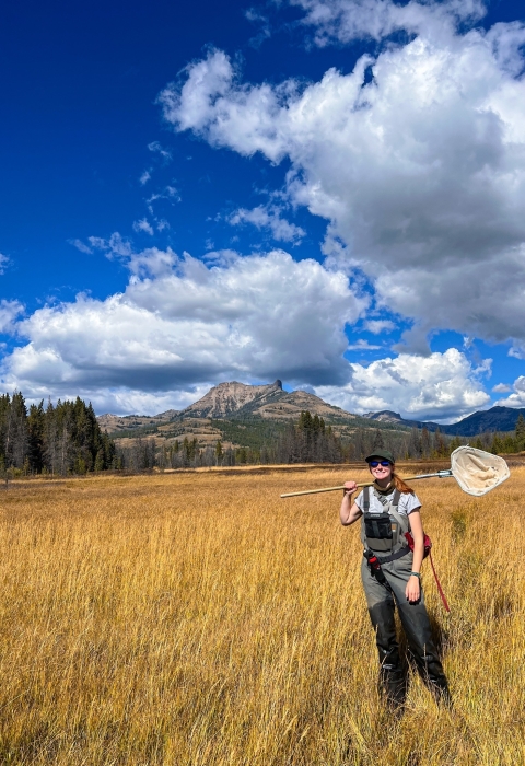 Woman standing in field holding a dipnet