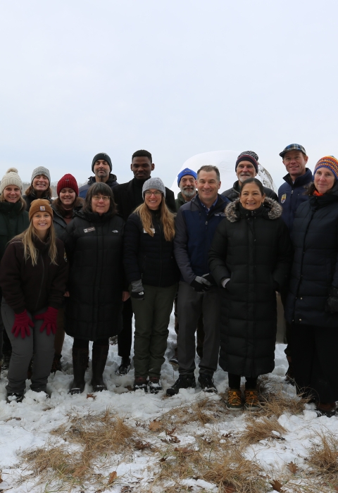 A smiling group stands in a snowy marsh