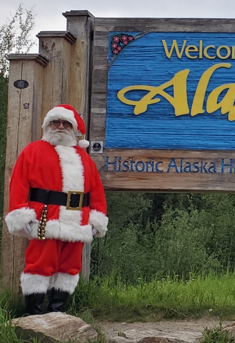 Watercraft inspector, Steve Wogtech, posed in Santa suit in front of Welcome to Alaska sign.