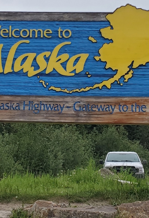 Watercraft inspector, Steve Wogtech, posed in Santa suit in front of Welcome to Alaska sign.