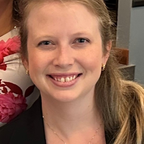 A white woman smiles into the camera and wears her blonde hair in a low ponytail.