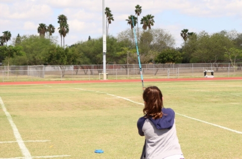 A young woman casts a line with a fishing rod at a plastic fish.