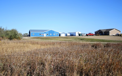 A blue office building and a gravel driveway leading to it. 