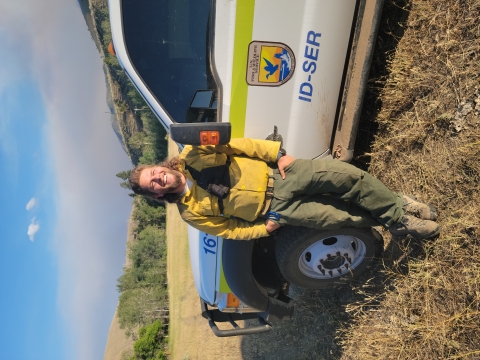A smiling man in fire clothes leaning against an FWS truck