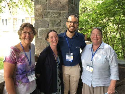 Four people stand and smile
