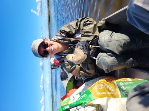 person in boat holds waterfowl