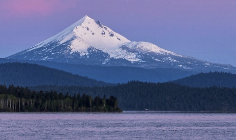 a body of water with a snow covered mountain in the background