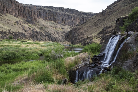 A small waterfall is in the right side of the frame and the left side is a river flowing into a canyon