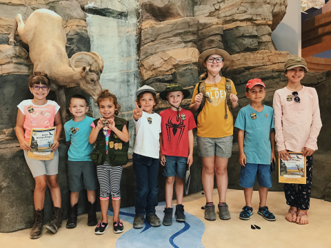 Group of junior rangers standing in front of a visitor center display exhibit