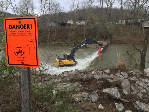 Crane removing dam with danger sign in the foreground