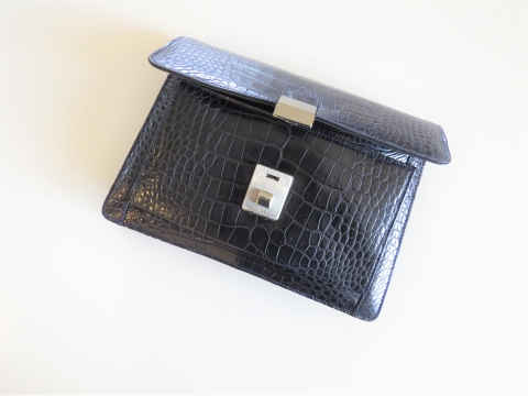 A close-up of a black alligator skin clutch.