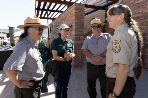 Four people talk in a group at an outdoor event