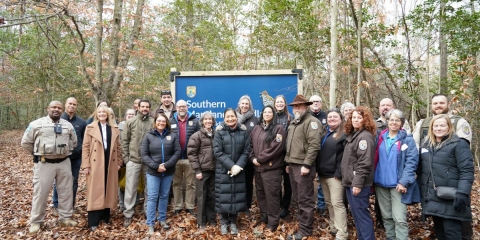 large group of people stand in front of National Wildlife Refuge sign