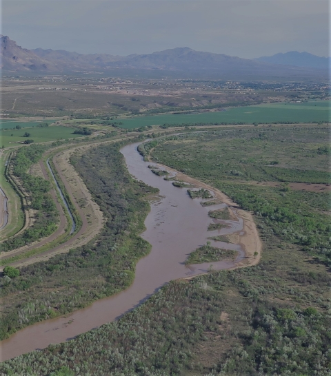 A winding river next to fields and agricultural land