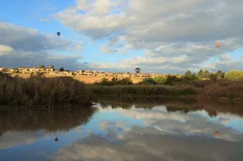 A river with hot air balloons taking off in the distance