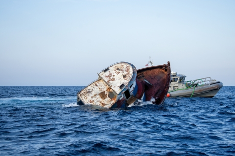 an old tugboat being sunk into the ocean