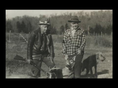 Two people and a dog, stand outside and pose with a deer they hunted.