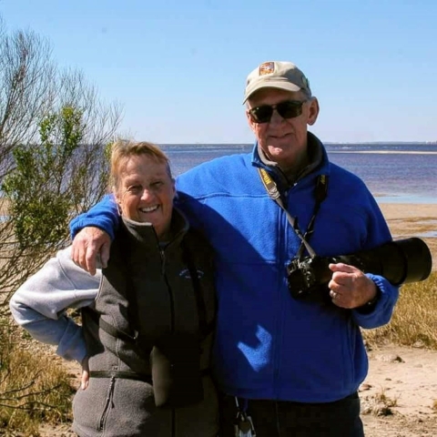 two people stand near a water body and smile