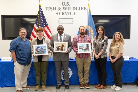 six people standing with artwork